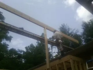 Carpenter setting a ridge beam over a new addition frame — Ice Dam Removal by Roofing Brothers in Harwood