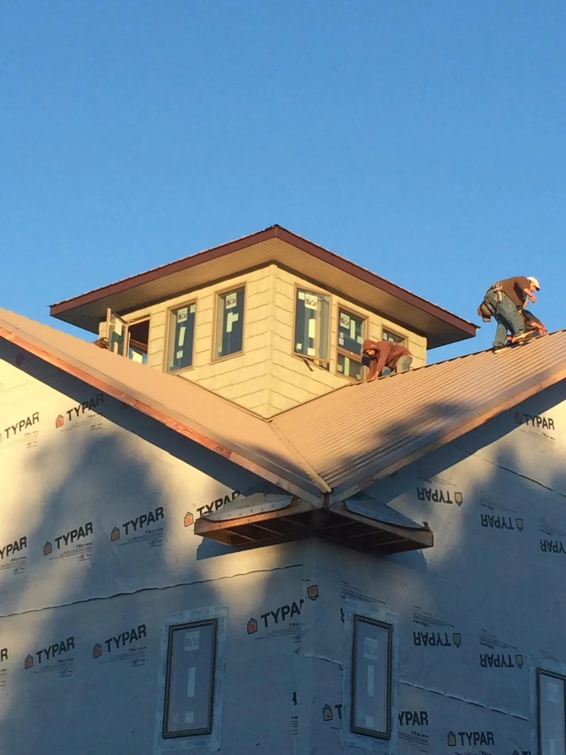 Roofers working around a rooftop cupola on a new metal roof at sunset — Roof Waterproofing in Harwood by Roofing Brothers